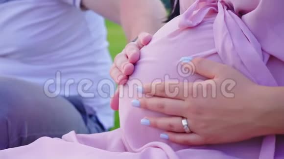 一对年轻夫妇的手放在孕妇的大肚子上等待孩子视频的预览图