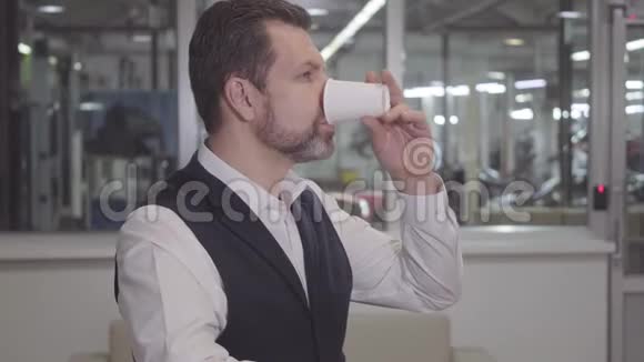 留胡子的白种人英俊男子喝咖啡回首修理店的肖像成功的年轻人在等待视频的预览图