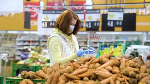 戴面具的女人在大流行病期间在杂货店买胡萝卜视频的预览图