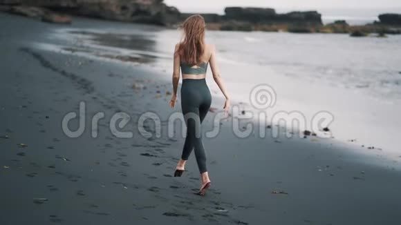 后景女人在黑滩散步把手臂举到高处转身视频的预览图