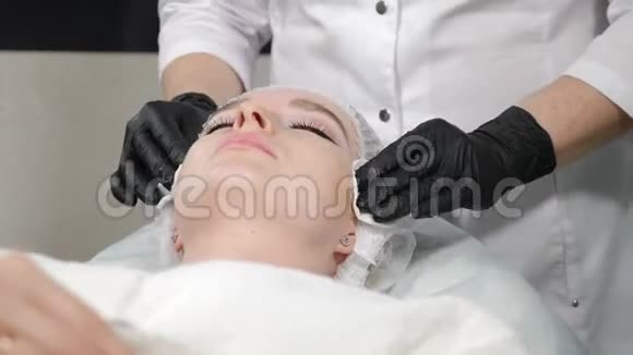 美容理念女性在沙龙面部清洁程序的特写镜头美容师擦拭客户皮肤视频的预览图
