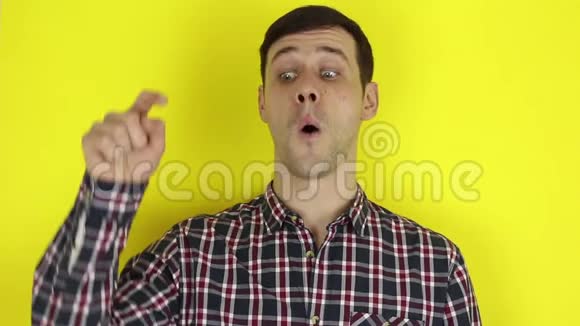 穿格子衬衫的帅哥露出食指黄色背景上的肖像视频的预览图