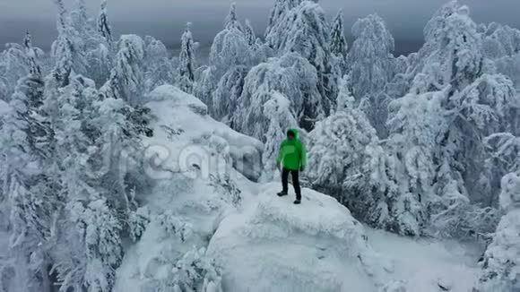 鸟瞰人站在山顶周围是白雪覆盖的森林视频的预览图