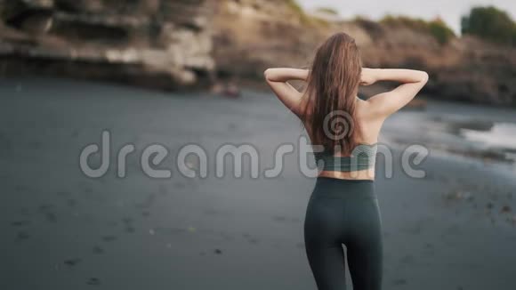 从侧面看女人走在海滩上转过身用手抚摸头发视频的预览图