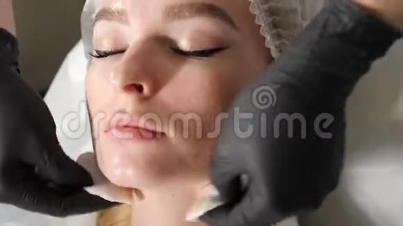 美容院女性面部清洁程序特写镜头美容师擦拭客户皮肤面部视频的预览图
