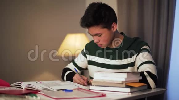 侧视特写疲惫的亚洲大学生在家做作业小帅哥在读写视频的预览图