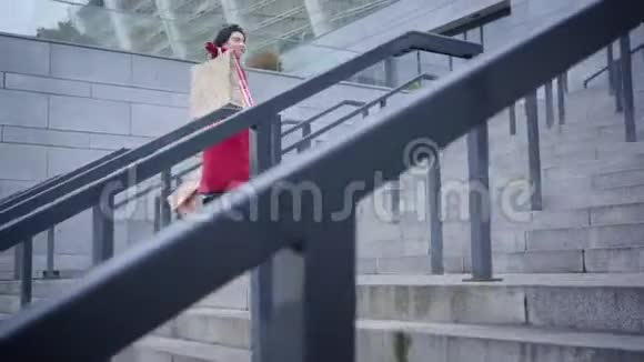 满意的微笑白种人女人穿着红色外套走上城市的楼梯快乐时尚的黑发女士视频的预览图