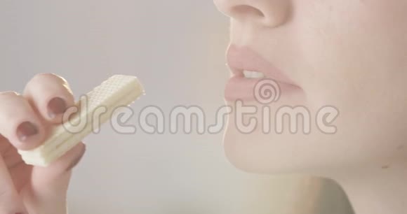 漂亮的女性吃脆皮香草华夫饼干享受美味的甜点口红和指甲的特写视频的预览图