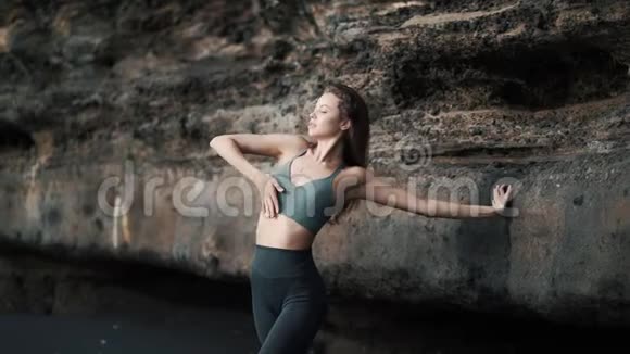 女人在悬崖附近的海滩上做伸展运动和舞蹈视频的预览图