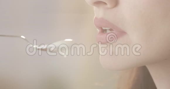 迷人的女性用勺子吃酸奶享受日记产品的味道口红和指甲的特写模糊的背部视频的预览图