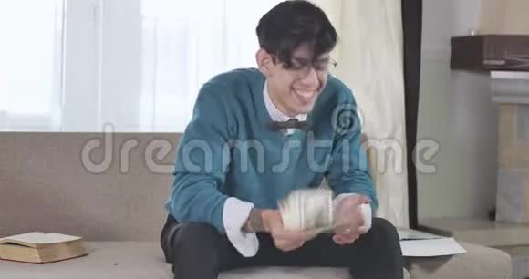 一个戴眼镜的富高加索男人坐在沙发上数着钱富有的年轻人微笑着视频的预览图