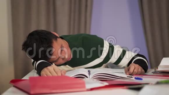 无法辨认的白种人男孩醒来时他的亚洲伙伴睡在桌子上疲惫大学的特写肖像视频的预览图