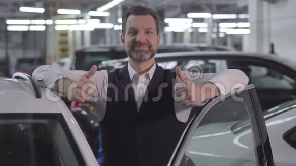 英俊的白种人商人站在旁边竖起大拇指打开汽车微笑的成年男人满意视频的预览图