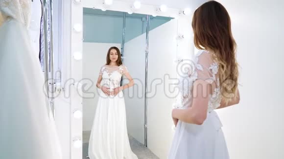 未来的新娘在沙龙里对着镜子试穿婚纱视频的预览图