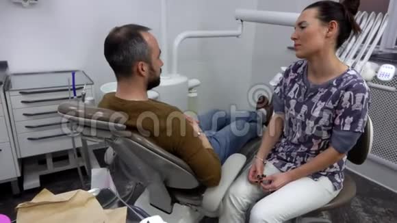 牙医正在与男性病人交谈以了解牙科问题视频的预览图