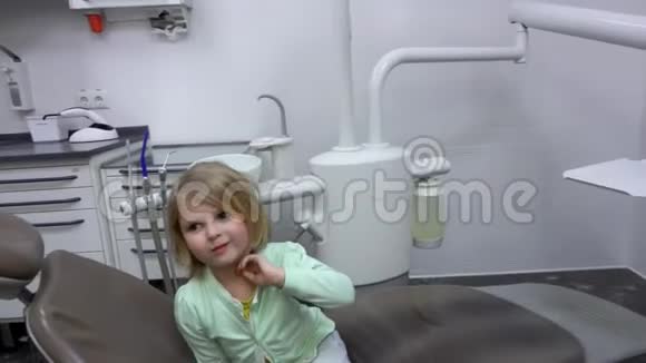 小可爱的女孩坐在一张特殊的牙医椅上视频的预览图