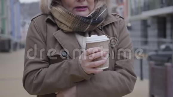 在城市街道上用冻僵的女性手捧着咖啡杯无法辨认的白人女性视频的预览图
