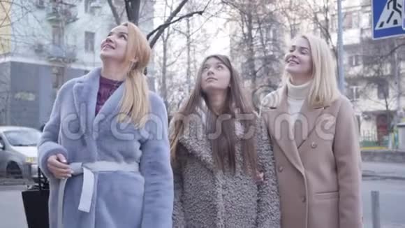 三个穿着秋装的美丽白种人女人抬头挥手和交谈的肖像时尚女孩在等视频的预览图