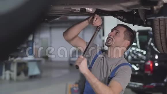 专业白种人汽车修理工拧紧汽车螺丝的肖像年轻的帅哥在修理店工作视频的预览图