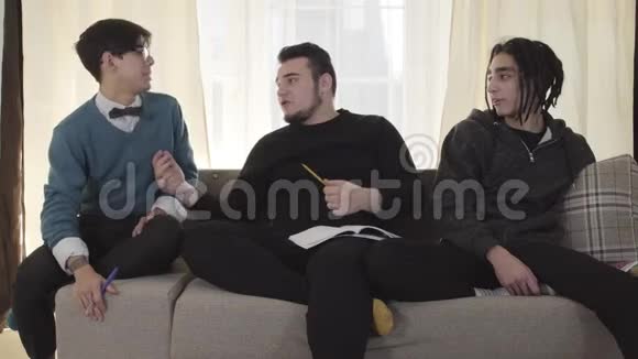 三个白人男性大学生坐在沙发上聊天成年朋友在室内聊天生活方式视频的预览图