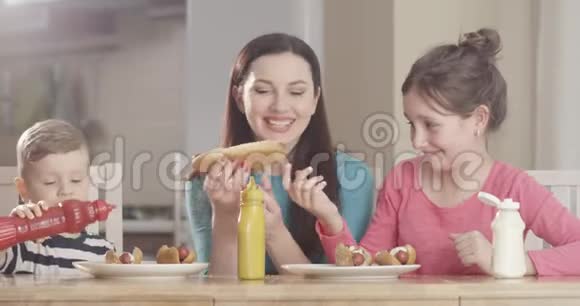 家庭制作热狗有乐趣和花费时间一起做饭在厨房餐桌上拍摄的红色镜头视频的预览图