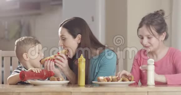 家庭在厨房餐桌上准备热狗和享受食物在红相机上拍摄美好时光视频的预览图