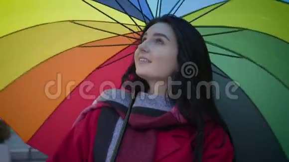一幅美丽的白种人女孩的特写肖像绿色的眼睛在背景上旋转着五颜六色的伞微笑着视频的预览图