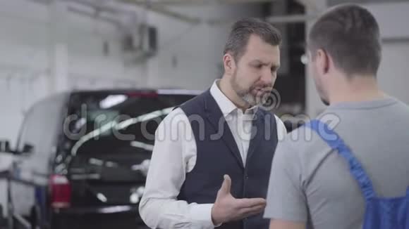 镜头在两个白种人的周围移动站在汽车的背景下愤怒的客户和男车交谈视频的预览图