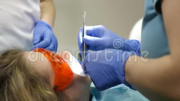 牙科诊所的概念看牙医检查年轻家庭病人的俯视图特写镜头医生和助理的合作视频的预览图