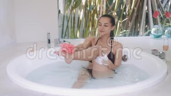 穿着黑色比基尼洗腿的快乐女士在房间里洗澡视频的预览图