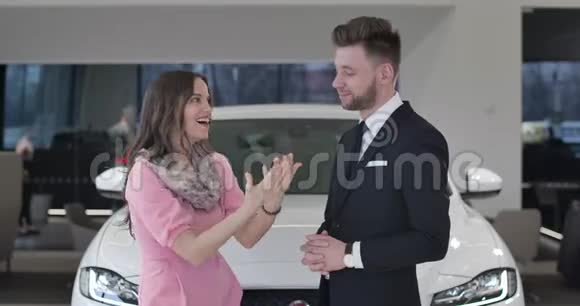 兴奋的高加索女性顾客在汽车经销商购买汽车的肖像女人吹嘘汽车钥匙商人视频的预览图