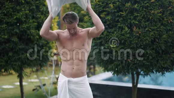 运动员用浴巾在花园里的树木附近擦拭身体视频的预览图