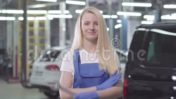 年轻的高加索女人站在交叉的手和微笑漂亮的女汽车修理工在工作场所摆姿势视频的预览图