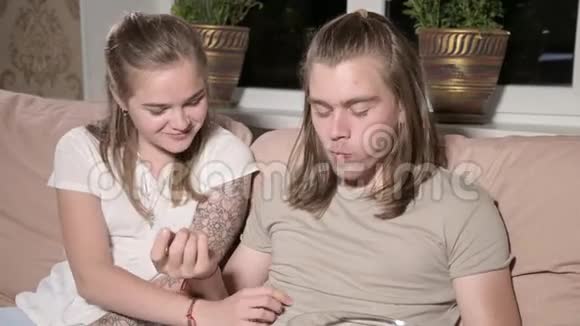 年轻快乐的夫妇正坐在沙发上女人把爆米花塞进男人嘴里视频的预览图