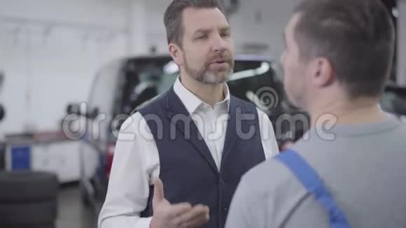 一幅特写照片描绘了一个不高兴的高加索人与面目全非的汽车修理工交谈成人自信商人视频的预览图