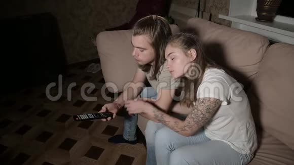 这对年轻夫妇正在看电视女人切换频道男人选择控制视频的预览图