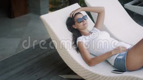 戴墨镜的躺在户外的躺椅上放松和享受假期视频的预览图