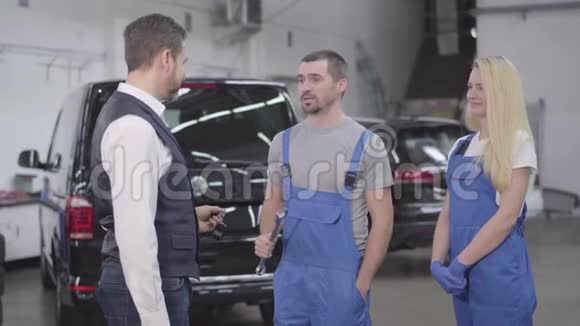 成人白种人汽车机械师从客户那里拿汽车钥匙并把它们交给女性助理站着的商人视频的预览图