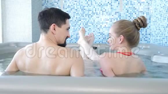 年轻情侣在温泉度假游泳池放松后景蜜月夫妇一起在游泳池里玩视频的预览图