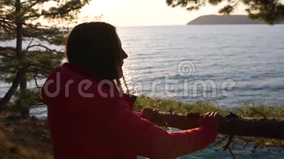 女孩在大自然中放松享受美丽的日落景观在海面上视频的预览图