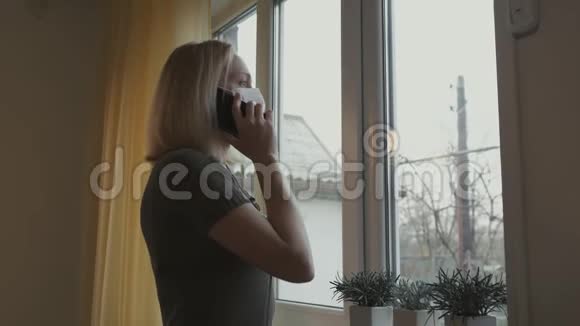 戴着医疗面具的女人在打电话站在窗口视频的预览图
