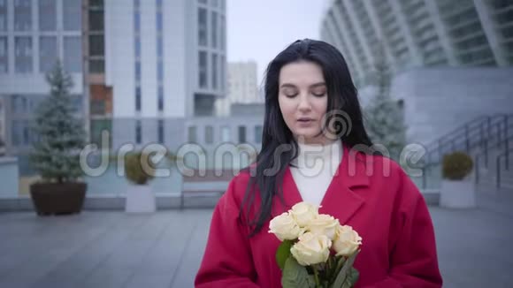 浪漫的年轻白种人女人闻黄玫瑰和看镜头的肖像时尚的黑发女士视频的预览图