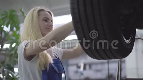 年轻美丽的白种人女人收紧车轮螺丝的肖像漂亮的女汽车修理工视频的预览图