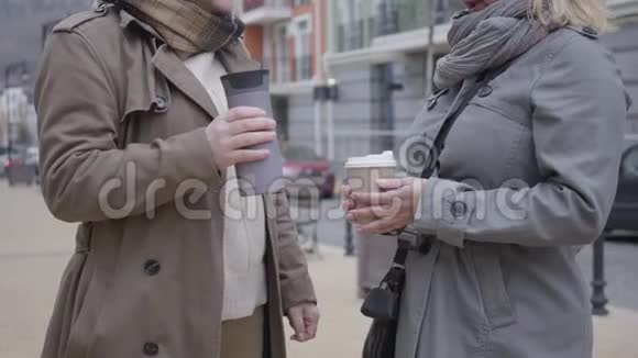 两个无法辨认的中年白种人女人在户外聊天穿着秋装的优雅退休人员站在城市视频的预览图