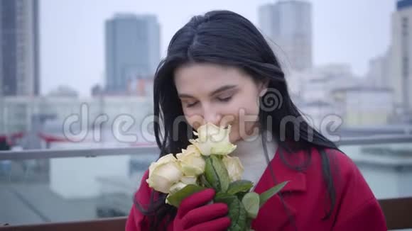 特写白种人年轻女子的肖像黑发闻着黄色的玫瑰和微笑站着的女士视频的预览图