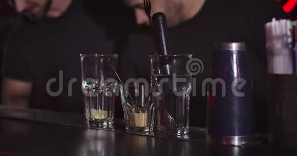 两个模糊的专业调酒师在鸡尾酒中添加香料和柠檬年轻的高加索人准备饮料视频的预览图