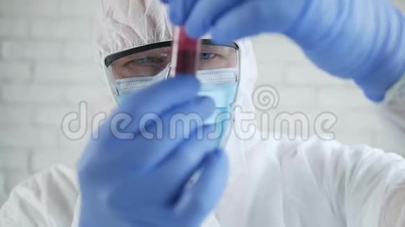 医院实验室的医生穿着防护服看着一个血液感染冠状病毒的管子视频的预览图