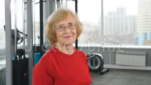 在健身房运动时一位令人愉快的老妇人举起杠铃进行胸肌训练的肖像健康活跃的老人视频的预览图