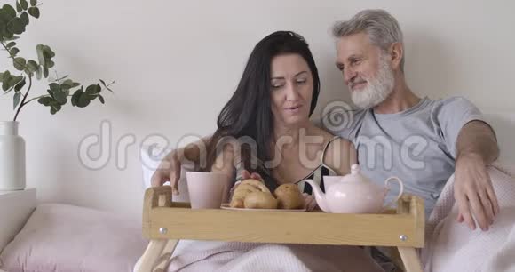 快乐的高加索夫妇谈话和闻新鲜牛角面包的肖像积极成熟的男人和女人视频的预览图