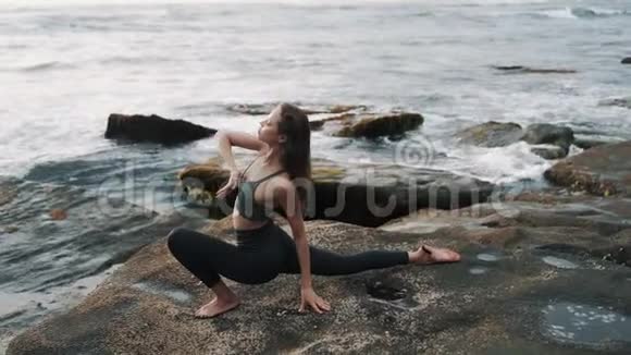 女孩在日落时分站在石头上与海浪搏斗视频的预览图